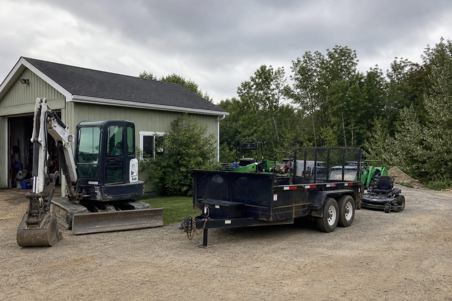 Landscaping equipment and a trailer parked outside a small commercial yard in late summer
