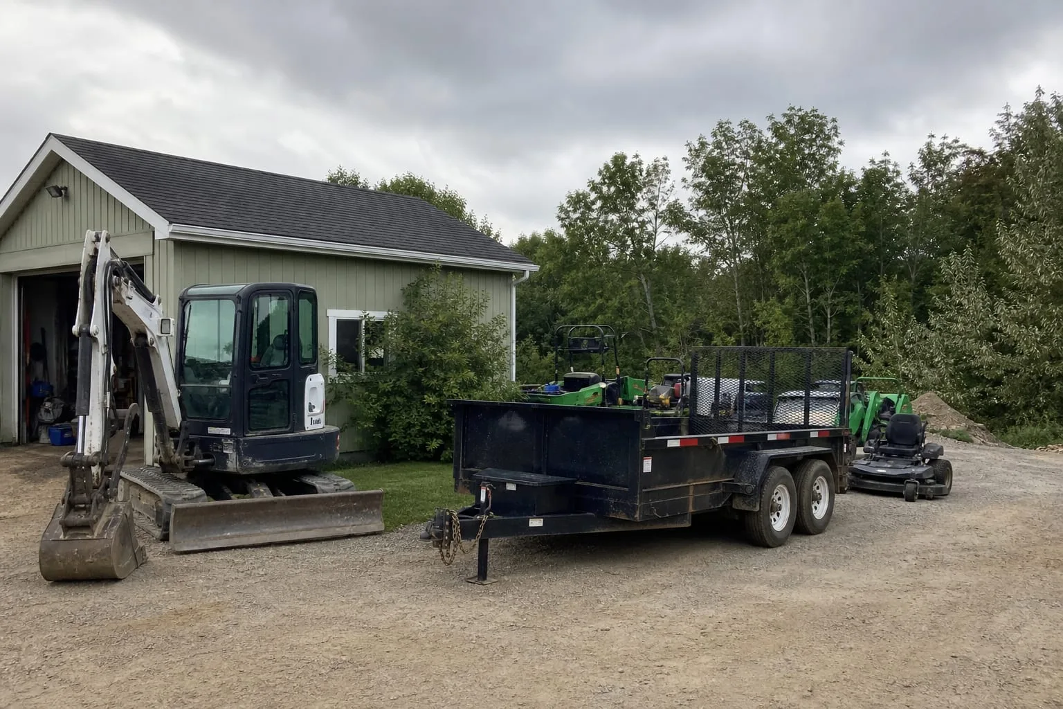 Landscaping equipment and a trailer parked outside a small commercial yard in late summer